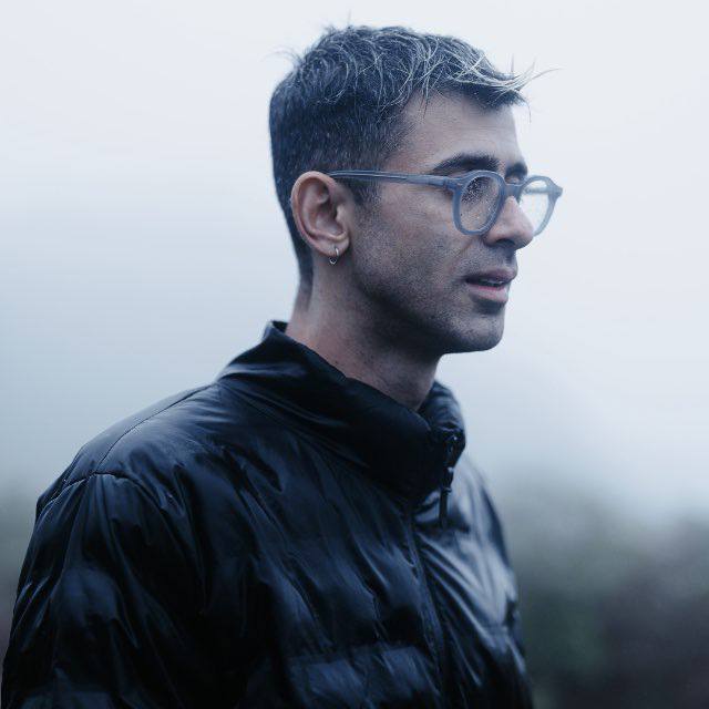 Sharif Nouri in profile, in round glasses and a black puffer jacket